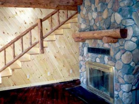 Log staircase beside a stone fireplace