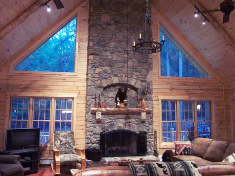 Great room with a two-story stone fireplace and vaulted log ceiling