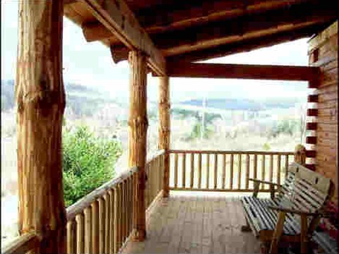 Covered log porch with railing and a view of the hills